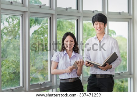 Asia students read a book and use smart phone in Library with uniform Royalty-Free Stock Photo #337471259