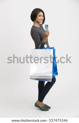 Happy Indian young woman with shopping bags and credit card