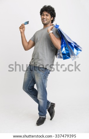 Happy young man with shopping bags and credit card on white.
