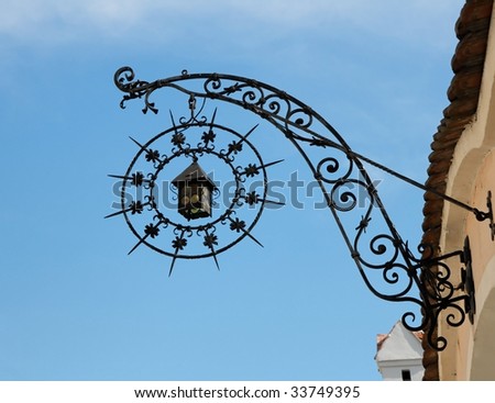 Medieval wrought iron shop sign in shape of lantern and star on sky background