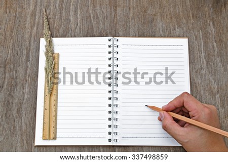 Hand Writing with Pencil on Notebook Paper on Wooden Table - Business Concept