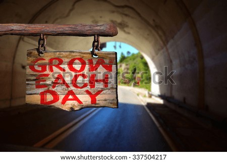 Grow each day motivational phrase sign on old wood with blurred background