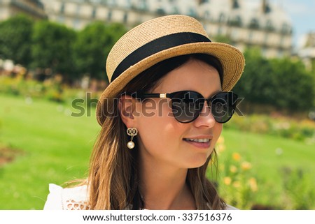 young attractive woman in hat, white dress, red bag and retro camera poses against Paris. Fashion and city style. 