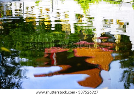 Blurry image of water abstract  pattern with fishes reflex blue sky and building.