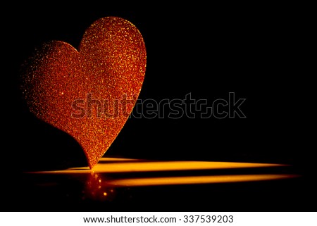 Heart made from falling golden glitter isolated on black. 