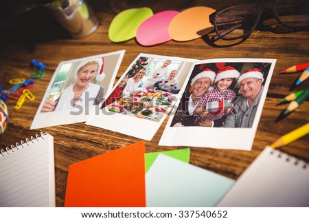 High angle view of office supplies and blank instant photos against smiling mature woman in santa hat toasting with white wine