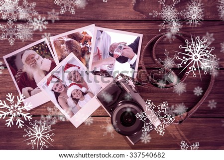 Smiling santa holding his glasses against instant photos on wooden floor