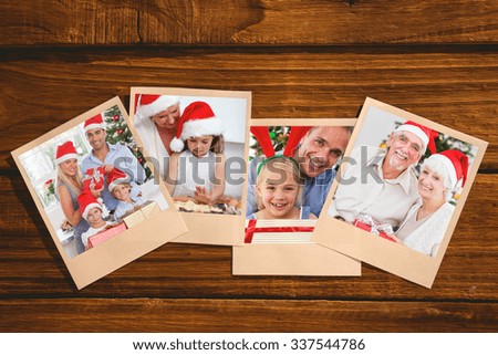 Smiling old couple swapping christmas gifts against instant photos on wooden floor