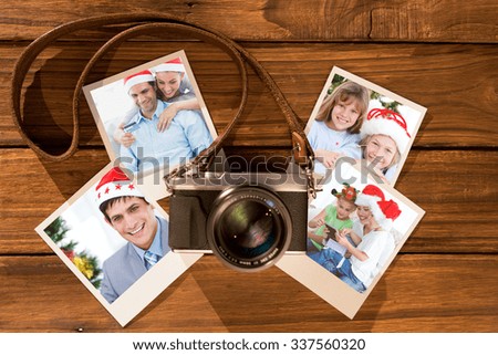 Cute couple in santa hats shopping online with laptop against instant photos on wooden floor