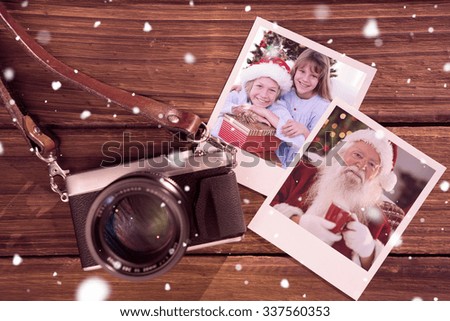 Smiling siblings holding Christmas gifts against instant photos on wooden floor
