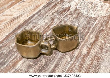 Small golden Mugs with handles/Mugs with handles/Small golden Mugs on a wooden table.