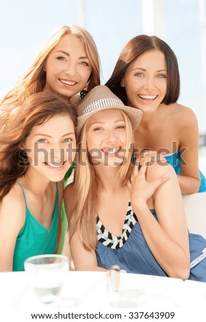 summer holidays and vacation concept - group of smiling girls in cafe on the beach