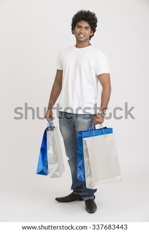 Happy smart young man posing with shopping bags on white background.