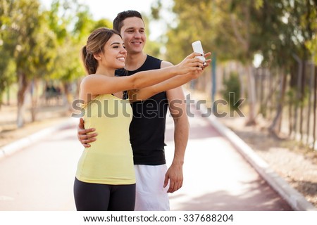 Good looking young couple taking a selfie with a smartphone before working out together in a running track
