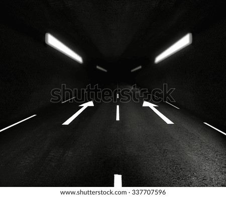 Road tunnel with lights and arrow signs on asphalt