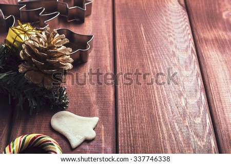 On a wooden desk background Christmas composition - candy cane, dough figurines, Christmas-tree branch Christmas balls, cookies, cones