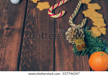 On a wooden desk background Christmas composition - candy cane, dough figurines, Christmas-tree branch Christmas balls, cookies, cones