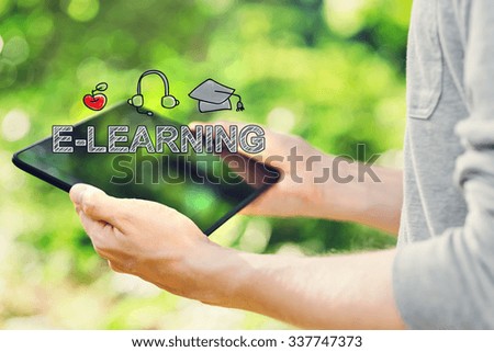 E-Learning concept with young man holding his tablet computer outside in the park