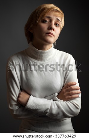 Doubt or distrust. The girl in a white sweater on the black background