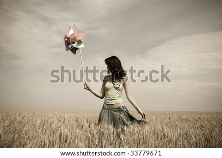 Girl with toy wind turbine at field, photo in age style
