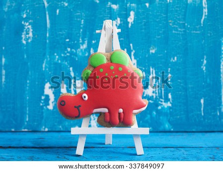 Homemade gingerbread cookie in the shape of dinosaurs on a wooden background. Space for text and selective focus.