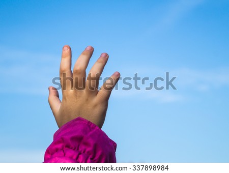 Child hand stretching to the blue sky