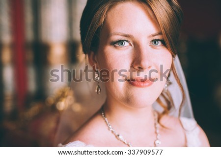 Gorgeous bride in wedding dress in luxury interior with diamond jewelry posing at home and waiting for groom. Romantic rich brunette bride in a luxurious wedding dress in expensive interior