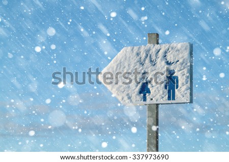 Sign of the toilet in the street, covered with snow
