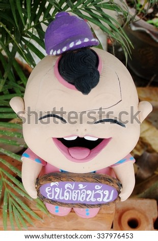boy figure welcome garden decorative ceramic doll standing in front of local shop display in THAILAND holding a plate with THAI alphabets Yin-Dee-Ton-Rab, means "welcome"