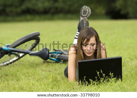 female student with laptop relaxing on the grass