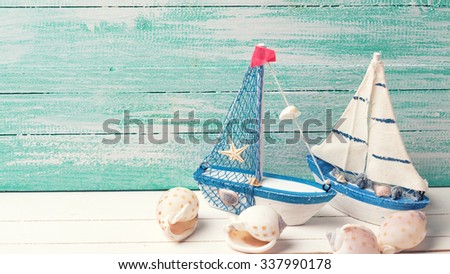 Decorative sailing boats and marine items on wooden background. Sea objects on wooden planks. Selective focus. Place for text. Toned image.
