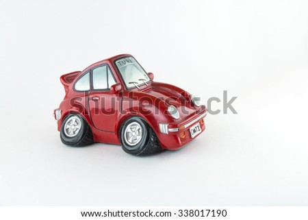 Small red car from side money-box on white