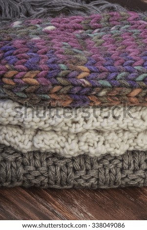 stack of cozy knitted sweaters / scarfs on a wooden table