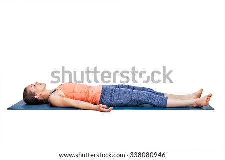 Beautiful sporty fit yogini woman relaxes in yoga asana Savasana - corpse pose in studio Royalty-Free Stock Photo #338080946