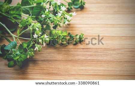 Vintage toned picture of oregano at the wooden background.