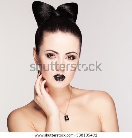 Beauty fashion model girl with funny bow hairstyle in the studio. Make-up and hairstyle. Black lipstick. Jewelry.