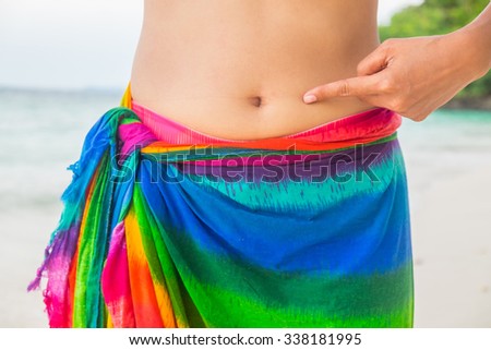 Closeup of woman point belly fat. Young slim woman point her abdomen. Diet and weight loss concept. Royalty-Free Stock Photo #338181995