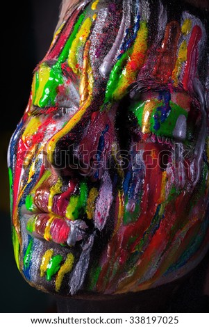 Girl with colored face painted. Art beauty image. Rainbow on face, wet style.