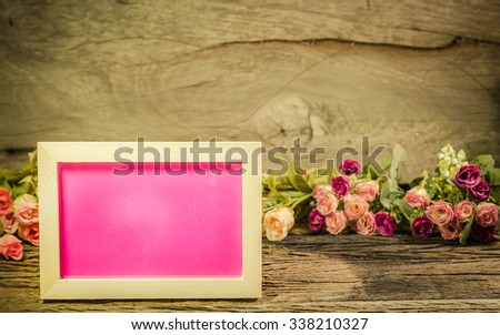 Photo frame with rose on the wooden table soft background vintage style.