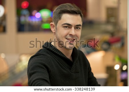 Young handsome man in a black knitted sweater photographing themselves on a cell phone