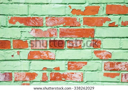 Old brick wall closeup texture with damaged layer of green paint, background photo
