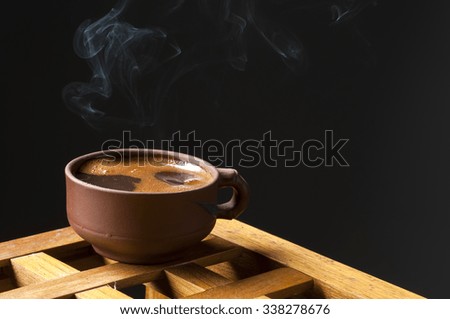 Black coffee cup with smoke over dark background