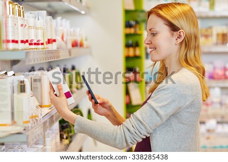 Young smiling woman scanning barcode with smartphone in a drugstore