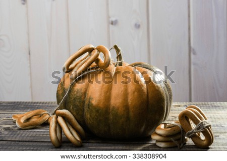 Photo closeup rustic autumn still life one big whole fresh orange pumpkin with bunches of hard oval cracknels bind with string on wooden table on timber background, horizontal picture 