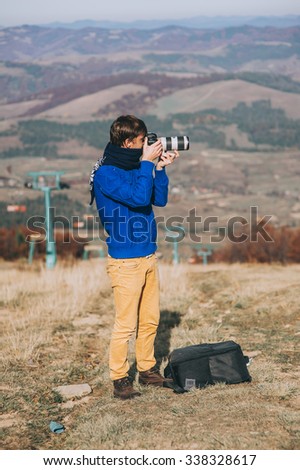 Man with a camera at the edge of a cliff overlooking the mountains below