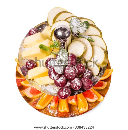 Delicious sliced fruits as a dessert platter covered with powdered sugar. Isolated on a white background.