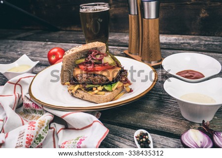 Cheeseburger with sauce, beer and rustic decor