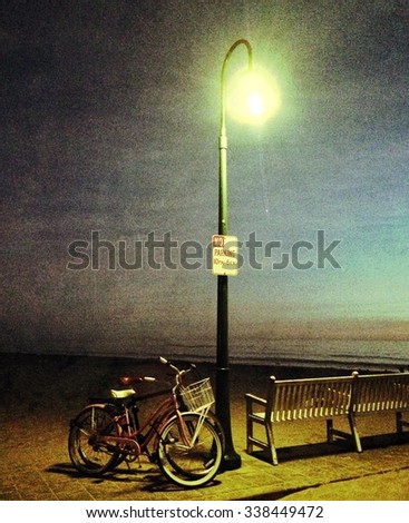 A Tall Street Light At Dusk With A No Parking Sign Iluminates An Empty Bench And Two Parked Bicycles