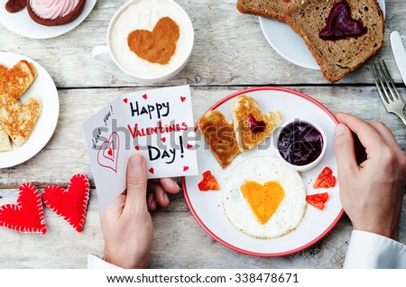 Men's hands hold a greeting card and a breakfast for Valentine's Day. toning. selective Focus