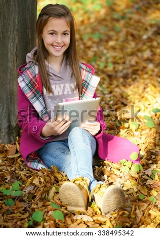 girl with autumn leaves search info for school on tablet